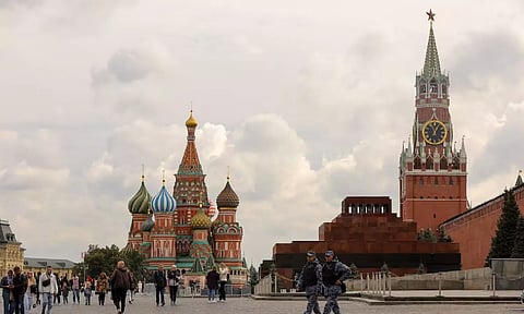 People walk across Red Square near St. Basil's Cathedral and the Kremlin's Spasskaya Tower in central Moscow