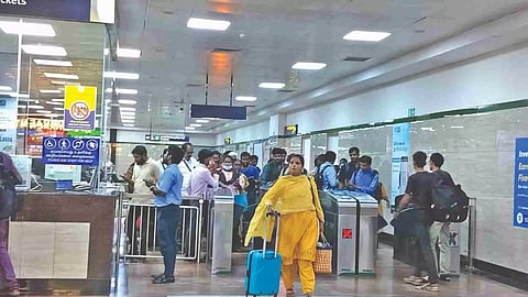 People wait at the automated fare collection system in one of the Metro stations
