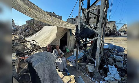 Displaced Palestinians, who fled their house due to Israel's military offensive, sit outside their tent, in Rafah, in the southern Gaza Strip (Reuters) 