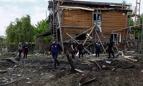 Police officers and war crimes prosecutors inspect a residential area hit by a Russian air strike (Reuters)