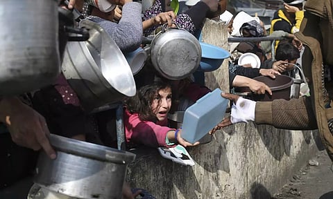 Palestinians line up for free food during the ongoing Israeli air and ground offensive on the Gaza Strip in Rafah (AP)