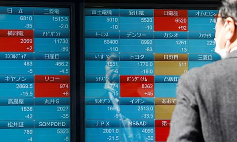 A man watches stock quotations on an electronic board outside a brokerage (Reuters)
