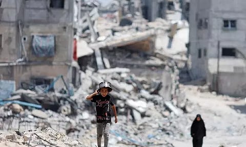 Palestinians walk by houses which were destroyed in an Israeli strike, amid the ongoing conflict between Israel and Hamas, in Khan Younis, in the southern Gaza Strip (Photo/Reuters)