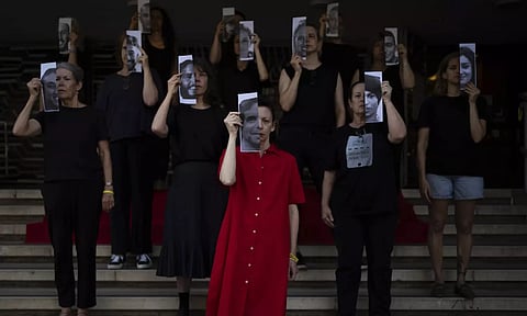Relatives and supporters of Israeli hostages held by Hamas in Gaza hold photos of their loved ones during a performance calling for their return in Tel Aviv (AP)