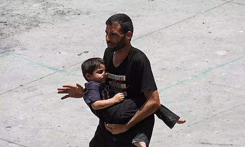 A man carries a child amid the ongoing conflict between Israel and the Palestinian Islamist group Hamas, in Gaza City (Reuters)