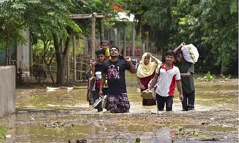 Villagers wade through a flooded area following rains in the aftermath of Cyclone Remal, in Hojai district, Assam (Photo/PTI)