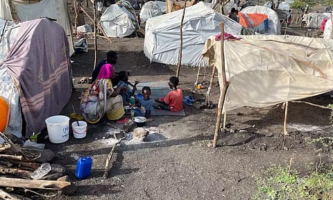 People sit by makeshift shelters near Awlala Camp (Reuters)