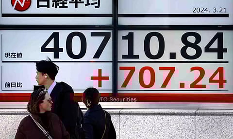 Passersby walk in front of an electric screen displaying Japan's Nikkei share average outside a brokerage in Tokyo (Reuters)