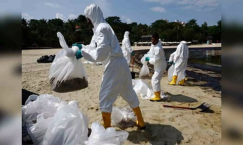 Workers clean up an an oil slick at Tanjong Beach in Singapore's Sentosa (Reuters)