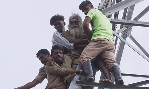 Auto drivers and fire fighters bringing down protesting Rajendran from high-tension power tower in Tiruchy on Wednesday