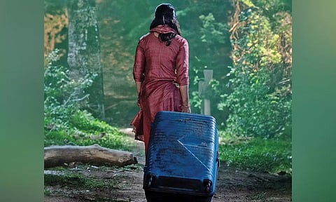 Rashmika turning backwards, walking with a suitcase inside a dense forest (Photo/X)