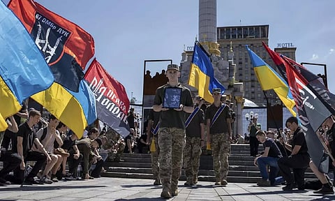 Ukrainian servicemen carry a portrait and coffin of British combat medic,Peter Fouche (AP)
