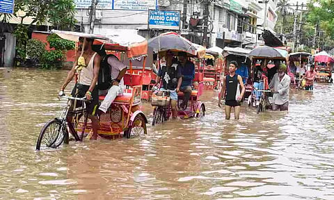 Rickshaw pullers carry passengers through a flooded street after incessant rains, in Guwahati (PTI)