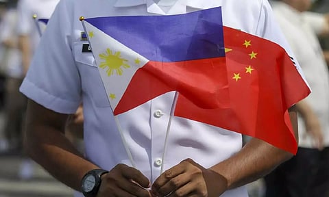 A member of the Philippine Coast Guard holds flags during the arrival of Chinese naval training ship (AP)