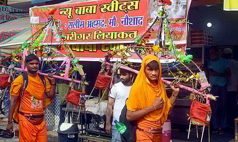  Kanwariyas walk past a shop on which banners with shopkeeper's name was put up on Kanwar Marg after an order issued by Uttar Pradesh Government (PTI)