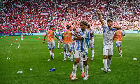Projectiles thrown by Morocco fans litter the pitch as Argentina's Cristian Medina celebrates his goal
