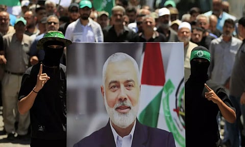 Hamas members hold a poster of Hamas political chief Ismail Haniyeh (AP)