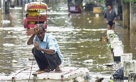 A man uses a makeshift thermacol boat to move through the flooded Anil Nagar area after rains, in Guwahati (PTI)