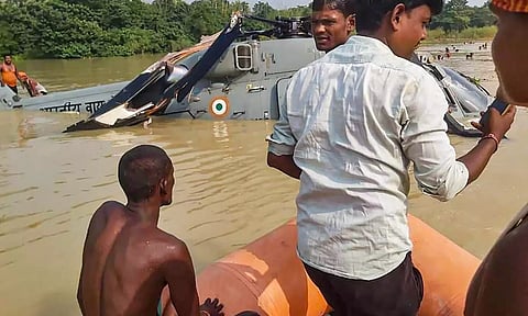 Locals assist in the rescue after Indian Air Force (IAF) helicopter made an emergency landing in a waterlogged area after it developed a snag, at Aurai in Muzaffarpur (PTI)
