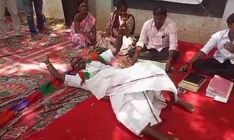 Councilor Mariappan rolls on the floor at Gram Sabha meeting protesting the merger on Wednesday