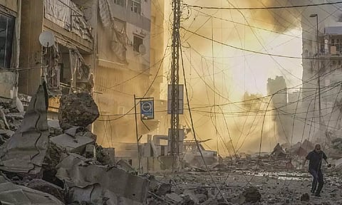 Man runs for cover as a smoke raises in the background following an Israeli airstrike in Dahiyeh, Beirut, Lebanon (AP)