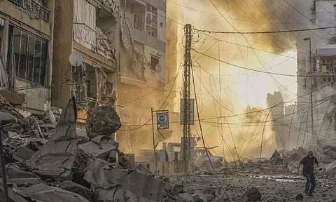 A man runs for cover as a smoke raises in the background following an Israeli airstrike in Dahiyeh, Beirut, Lebanon (AP)