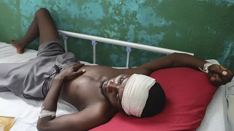 Germain Rivaldo, wounded by a bullet during armed gang attacks, lies on a bed at Saint Nicolas hospital in Saint-Marc (AP)