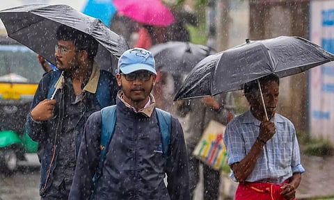 People holding umbrellas commute amid rains due to Spawn cyclone, in Bengaluru (PTI)