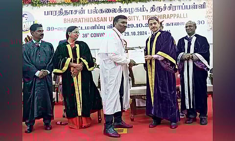 PhD scholar Israel Inbaraj handing over a petition to Governor Ravi during the Bharthidasan University convocation ceremony 