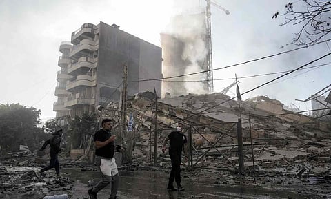 Residents run as smoke rises from a building that collapsed after it was hit by an Israeli airstrike (AP)