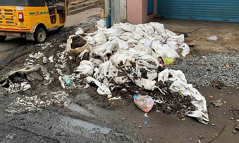 Vehicles go over the gunny bags full of silt stacked along the street