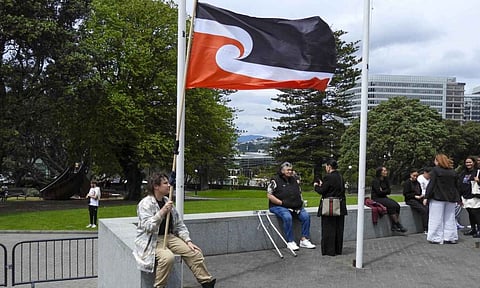 A protester against the Treaty Principles Bill sits outside Parliament in Wellington, New Zealand (AP)