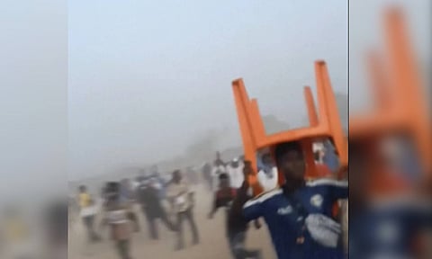 A man holds a chair on top of his head in a stampede (AP)