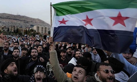 Syrian citizens wave the revolutionary flag and shout slogans (AP)