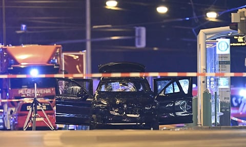 A damaged car sits with its doors open after a driver plowed into a busy Christmas market in Magdeburg (AP)