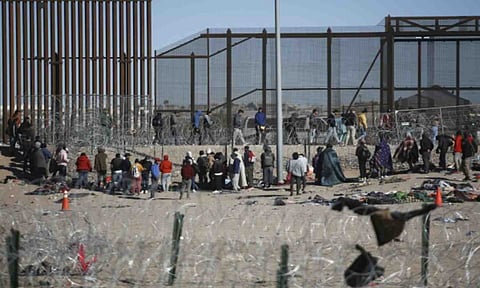 Migrants line up after being detained by U.S. immigration authorities at the U.S. border wall, seen from Ciudad Juarez, Mexico, Wednesday, Dec. 27, 2023. (AP /Christian Chavez)