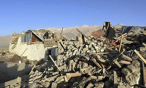 People stand amidst damaged houses in the aftermath of an earthquake in Tonglai Village (AP)