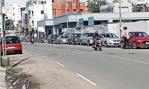 Two wheelers and cars parked on both sides of the Tiruvottiyur High road 