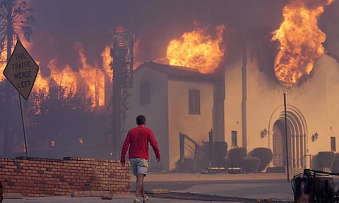 A man walks in front of the burning Altadena Community Church (AP)