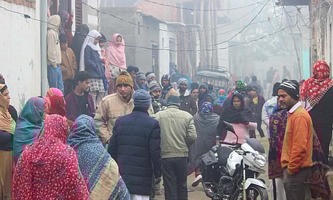 People gather at the locality where the bodies of five members of a family were found at their home, in Uttar Pradesh's Meerut
