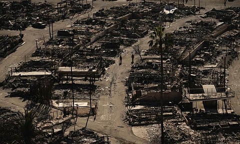 Firefighters walk along a road in a fire-ravaged community in the aftermath of the Palisades Fire in the Pacific Palisades neighborhood of Los Angeles 