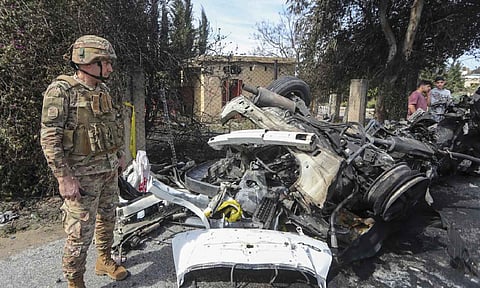 A Lebanese army officer stands next to a destroyed car in the southern outskirts of Tyre, Lebanon (AP) 
