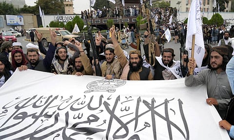 Taliban fighters hold their flag as they celebrate one year since they seized the Afghan capital, Kabul, in front of the U.S. Embassy in Kabul, Afghanistan (AP)