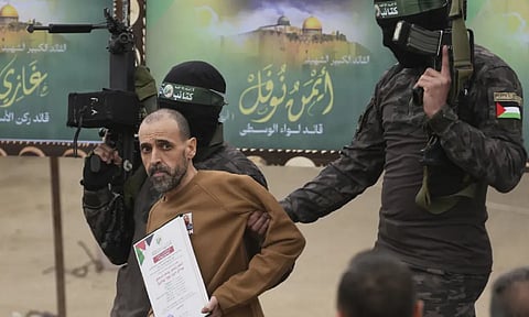 Israeli captive Eli Sharabi, who had been held hostage by Hamas in Gaza since Oct 7, 2023, is escorted by Hamas fighters before being handed over to the Red Cross in Deir al-Balah