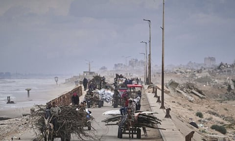 13 Displaced Palestinians, carrying their belongings, wood and other items, move between southern and northern Gaza along a beach road away from the areas where the Israeli army is operating after Israel's renewed offensive in the Gaza Strip, in the outskirts of Gaza City (AP)