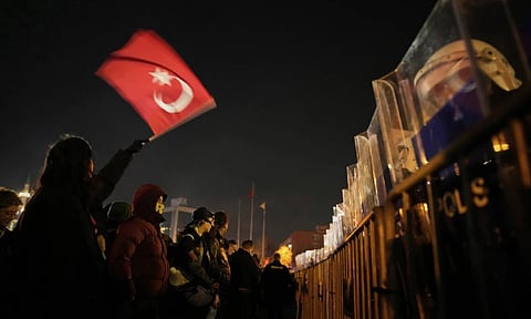 A protester waves Turkish flag during a protest against the arrest of Istanbul's Mayor Ekrem Imamoglu, outside Caglayan courthouse, in Istanbul (AP)