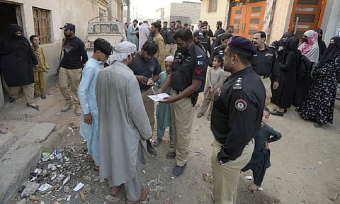 A Police officer checks documents of a resident during a search operation against illegal immigrants, at a neighbourhood of Karachi, Pakistan, Nov 2, 2023 (AP) 