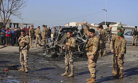 Lebanese army members gather near a charred car that was hit by an Israeli strike in the south coastal town of Ghazieh Lebanon. (AP)