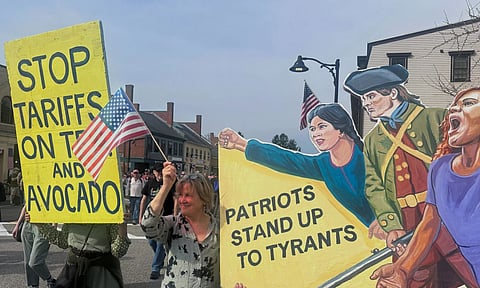 Protesters hold signs during a parade honoring the 250th anniversary of the American Revolution (AP)