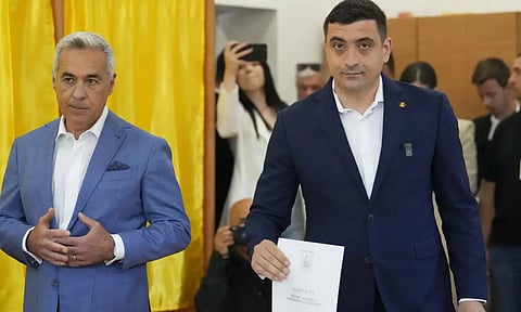 Presidential candidate George Simion, right, casts his vote next to Calin Georgescu, winner of the first round of last year's annulled election, during the first round of the presidential election redo in Bucharest, Romania (AP)